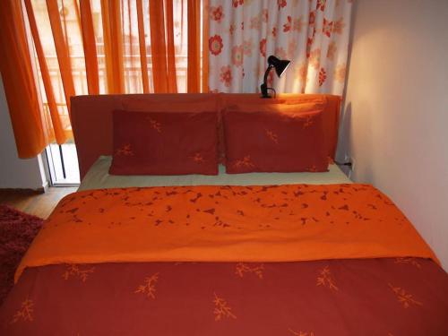 uma cama com lençóis laranja e um gato preto sentado nela em The Ideal House In The City Center em Veria