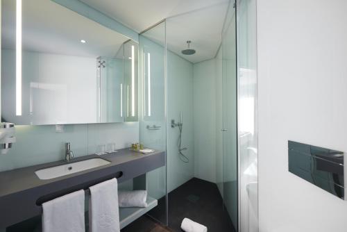 a bathroom with a shower, sink, and mirror at Eurostars Heroismo in Porto