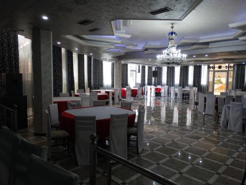 a banquet hall with white tables and chairs and a chandelier at Garden Palase Hotel in Fier