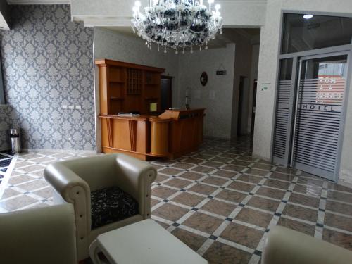 a lobby with a desk and a chandelier at Garden Palase Hotel in Fier