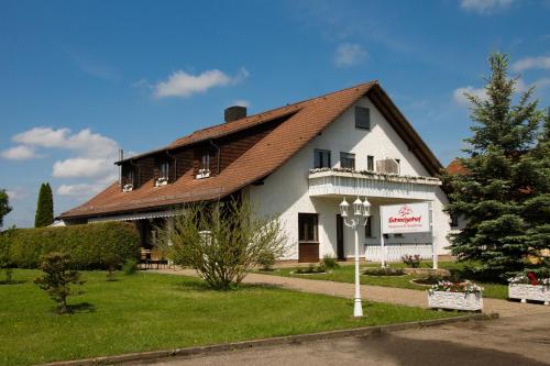 ein großes weißes Gebäude mit braunem Dach in der Unterkunft Gästehaus Schweizerhof in Böbingen an der Rems