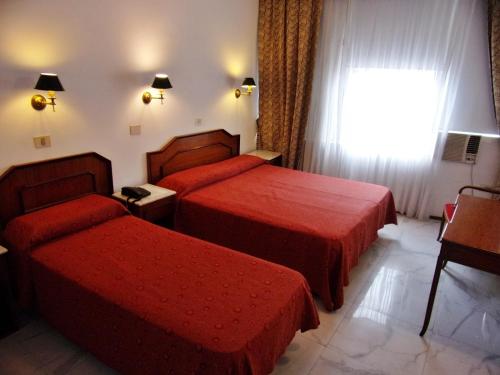 a hotel room with two beds and a window at Hotel Tres Sargentos in Buenos Aires