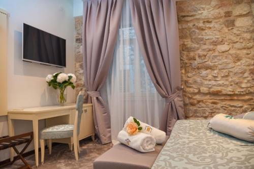 a bedroom with a bed and a desk and a window at Heritage Hotel Antique Split in Split