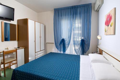 a bedroom with a blue bed and blue curtains at Hotel La Cappuccina in Riccione