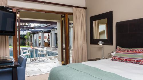 a bedroom with a bed and a television and a patio at Manor 38 in Port Elizabeth