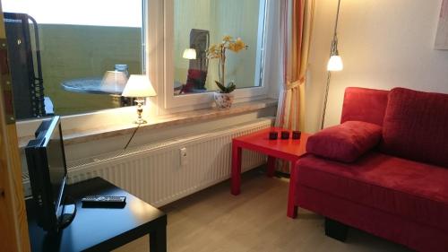 a living room with a red couch and a window at Ferienwohnung "Traumblick" - Selbstversorger in Braunlage