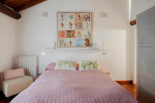 um quarto com uma cama com um edredão rosa e uma cadeira em Appartamento San Michele em Milão