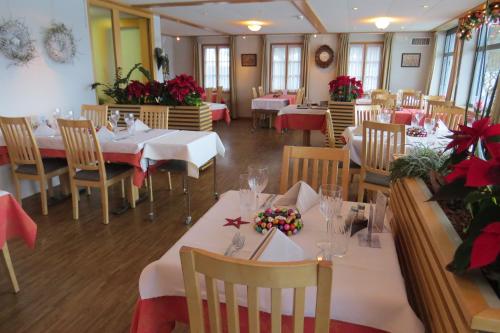 een restaurant met tafels en stoelen met rode bloemen erop bij Hotel Restaurant Sternen in Guggisberg