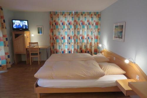 a bedroom with a bed and a tv in it at Hotel Restaurant Sternen in Guggisberg