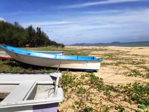 a blue and white boat sitting on the beach at Semarak Beach Inn in Dungun