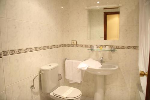 a white bathroom with a toilet and a sink at Hostal Ancla Dorada in Vigo