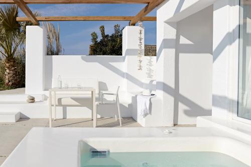 a white house with a table and chairs and a pool at Amare Mykonos in Tourlos