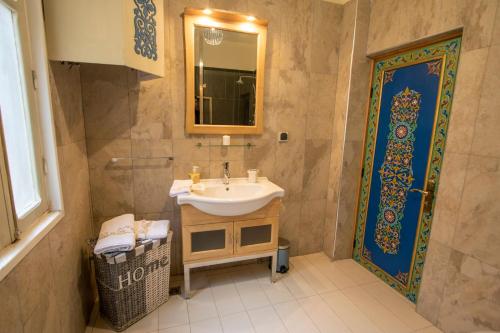 a bathroom with a sink and a mirror and a door at Riad Fes Nass Zmane in Fès