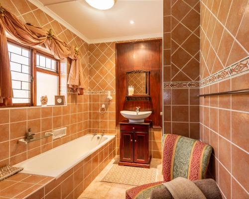 un baño con bañera y lavabo en Brown Jug Guest House, en Hermanus