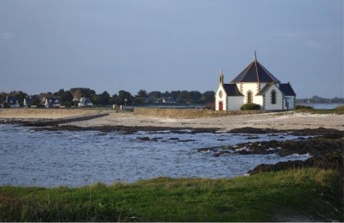 a church on the shore of a body of water at Hôtel Restaurant Le Mur du Roy in Sarzeau