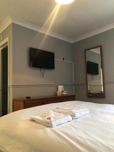 a bedroom with a white bed with a television on the wall at The Crown Hotel in Ryde