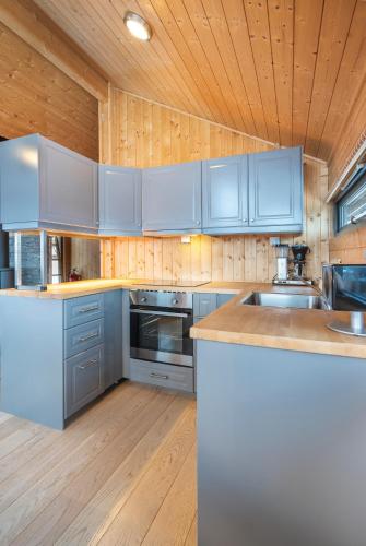 a kitchen with blue cabinets and a wooden ceiling at Liapark in Ål