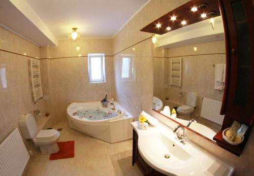 a bathroom with a tub and a toilet and a sink at Monterai Resort in Poiana Brasov