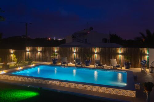 a swimming pool at night with lights on a fence at villa yvonne,private pool,private parking 1,7 km from the beach in Albufeira