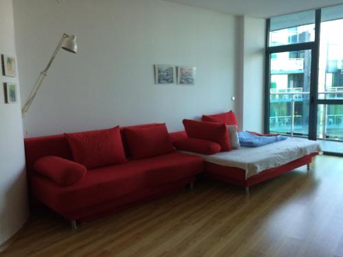 ein Wohnzimmer mit einem roten Sofa und einem großen Fenster in der Unterkunft Sea view, 2 room apartment 703, Primorsko in Primorsko