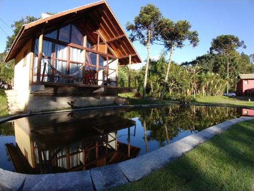 uma casa com um reflexo num lago em Pousada Silvestre em Visconde de Mauá