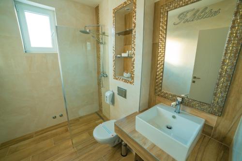 a bathroom with a sink and a toilet and a mirror at Motel Felikitas in Laktaši