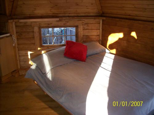 uma cama num chalé de madeira com uma almofada vermelha em The Hobbit House em Fort William