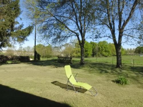 a yellow chair sitting in the grass in a park at Gîte Rouge Calme et Nature in Allas-Bocage