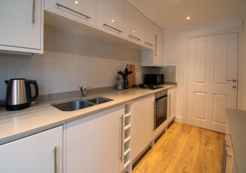 a kitchen with white cabinets and a sink at Wakeford Cottage in Worthing