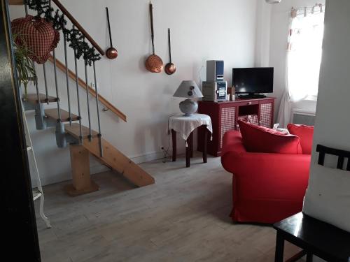 a living room with a red couch and stairs at Gîte Rouge Calme et Nature in Allas-Bocage