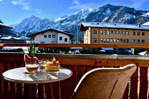a table with a cake on a balcony with mountains at Boutique Hotel Pinzgauerhof in Kaprun
