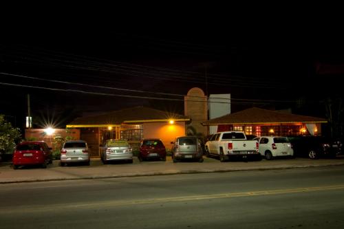 a group of cars parked in a parking lot at night at Pousada Le Baron in Praia do Frances