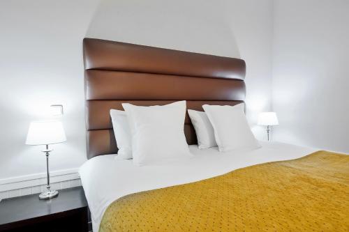 a bedroom with a large white bed with a brown headboard at La Boutique in Prague