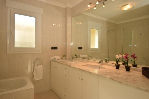 a bathroom with a sink and a tub and a mirror at Hotel Apartamento Residencia Parques Casablanca in Benissa