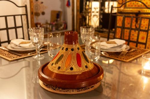 a table with a vase on top of a table with glasses at Dar El Bali in Fès