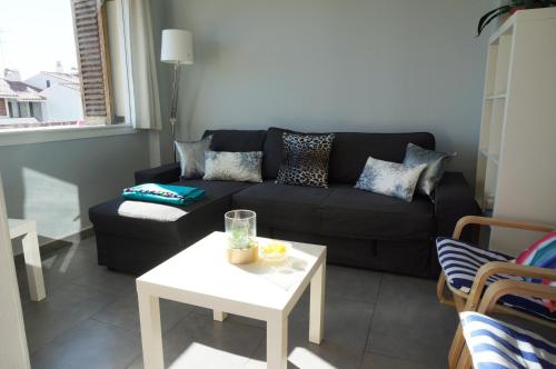a living room with a black couch and a table at Cala Balmins Sea View in Sitges