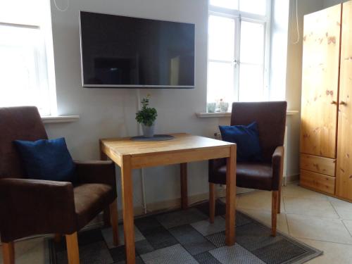 a room with a table and two chairs and a television at Apartment Muschel im Gästehaus Heeren in Krummhörn