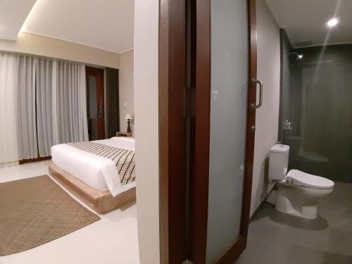 a bedroom with a bed and a bathroom with a toilet at Kyumari in Ubud
