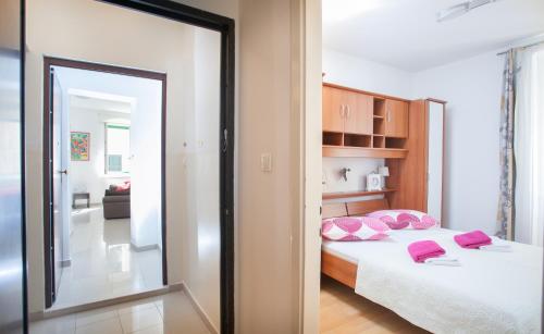 1 dormitorio con cama con almohadas rosas y espejo en Apartments Goda Center Of Split, en Split