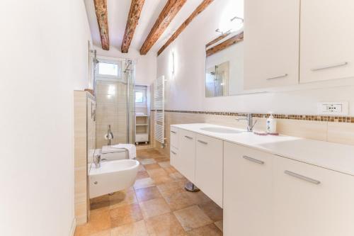 uma casa de banho com armários brancos, um lavatório e um WC. em Mimosa Apartment em Veneza