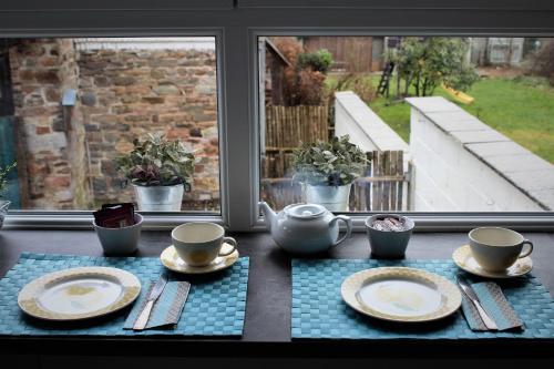 a table with plates and cups on a table with a window at Gite Le Cerf Pantin in Saint-Hubert