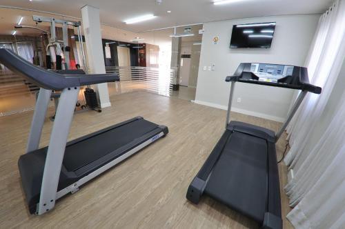 a gym with a treadmill and a flat screen tv at Klein Ville São Leopoldo in São Leopoldo