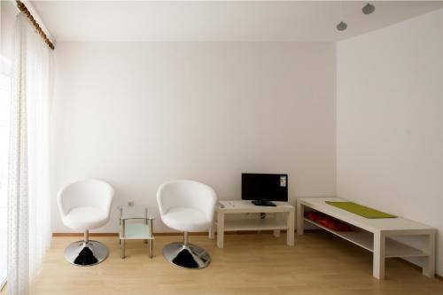 a living room with two white chairs and a desk at Friendly People's Guest House in Zadar