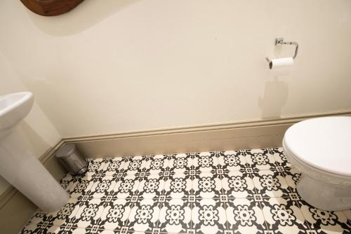a bathroom with a toilet and a black and white tile floor at Apartment 1 The Grove in Durham