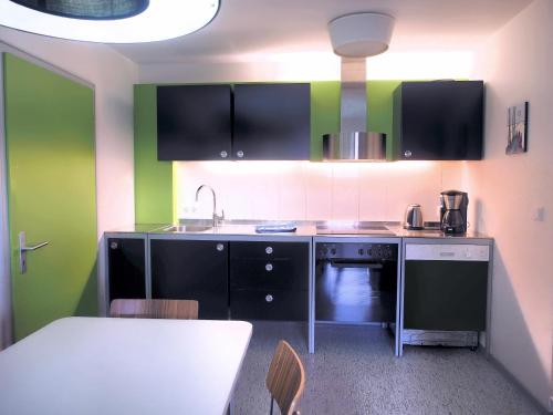 a kitchen with green and black cabinets and a table at Künstlerhaus Arthotel in Geislingen