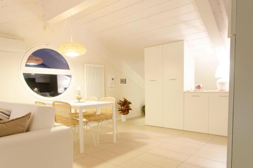 ein weißes Wohnzimmer mit einem Tisch und einem Fenster in der Unterkunft Dante 124 | Appartamenti a Riccione in Riccione