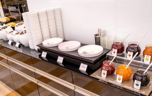 a counter with white plates and jars of food at Grandium Hotel Prague in Prague