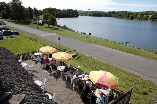 a group of people sitting at tables with umbrellas near a lake at Rasta Lilla Edet in Lilla Edet