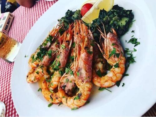 a white plate of shrimp and broccoli on a table at Apartments Vila Marija in Kotor