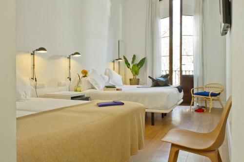 een hotelkamer met 2 bedden en een stoel bij Som Nit Born in Barcelona